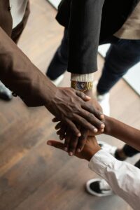 Diverse hands uniting in teamwork inside a professional office environment.